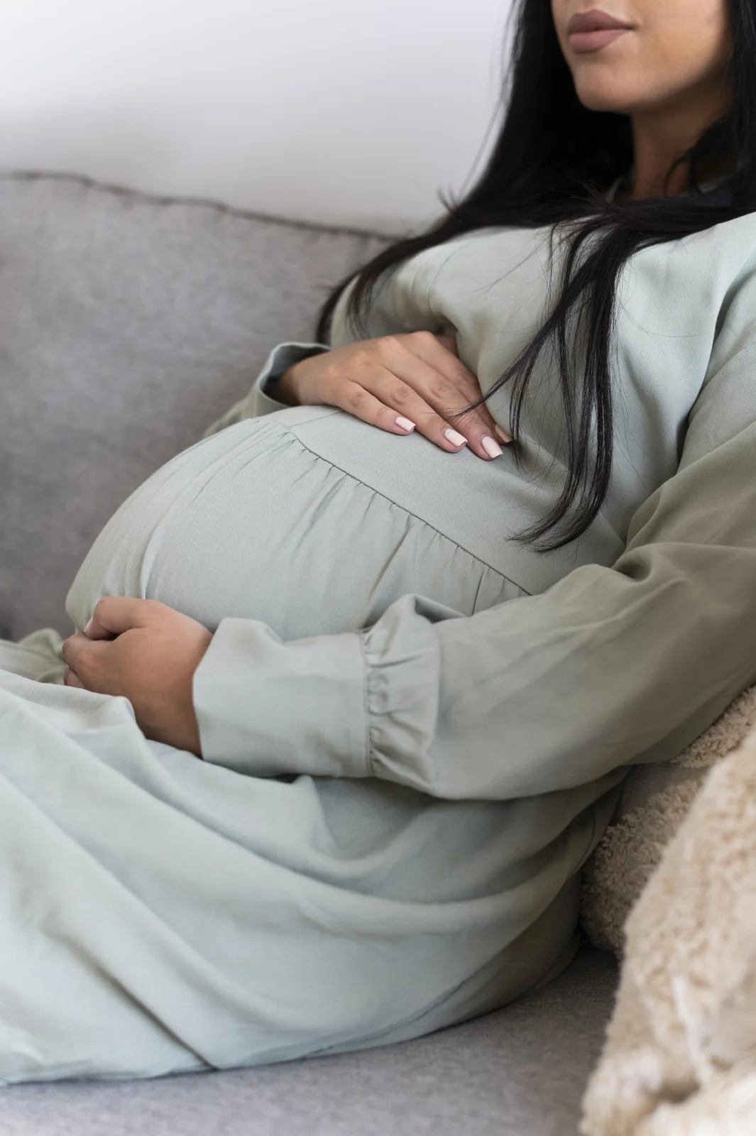 A pregnant woman resting with her hands on her belly