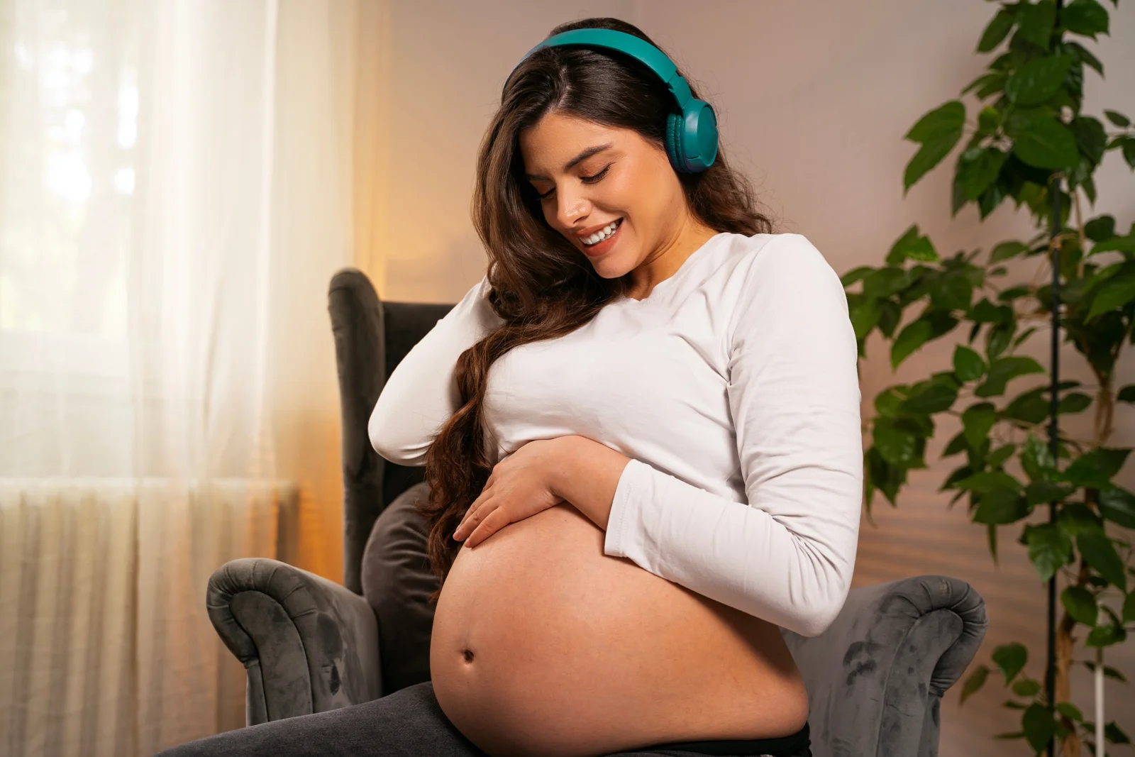 A pregnant woman smiling while touching her belly